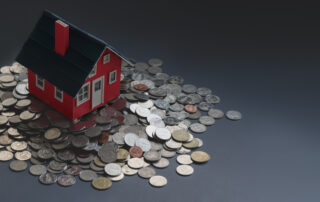 Carton miniature house placed on table with stack of coins