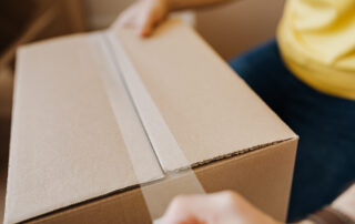 Crop man sealing cardboard box with tape