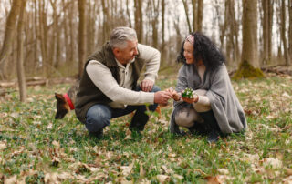 Happy elderly couple in love with fresh flowers and dog in forest