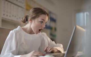 Woman in white long sleeve shirt using silver laptop computer