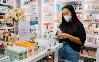 Woman with face mask holding an alcohol bottle