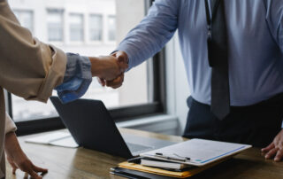 Crop colleagues shaking hands in office