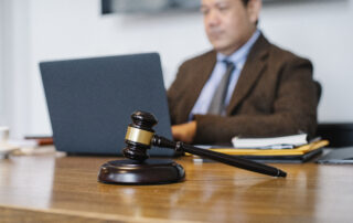 Crop asian judge working on laptop in office