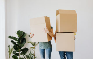 Couple carrying cardboard boxes in living room