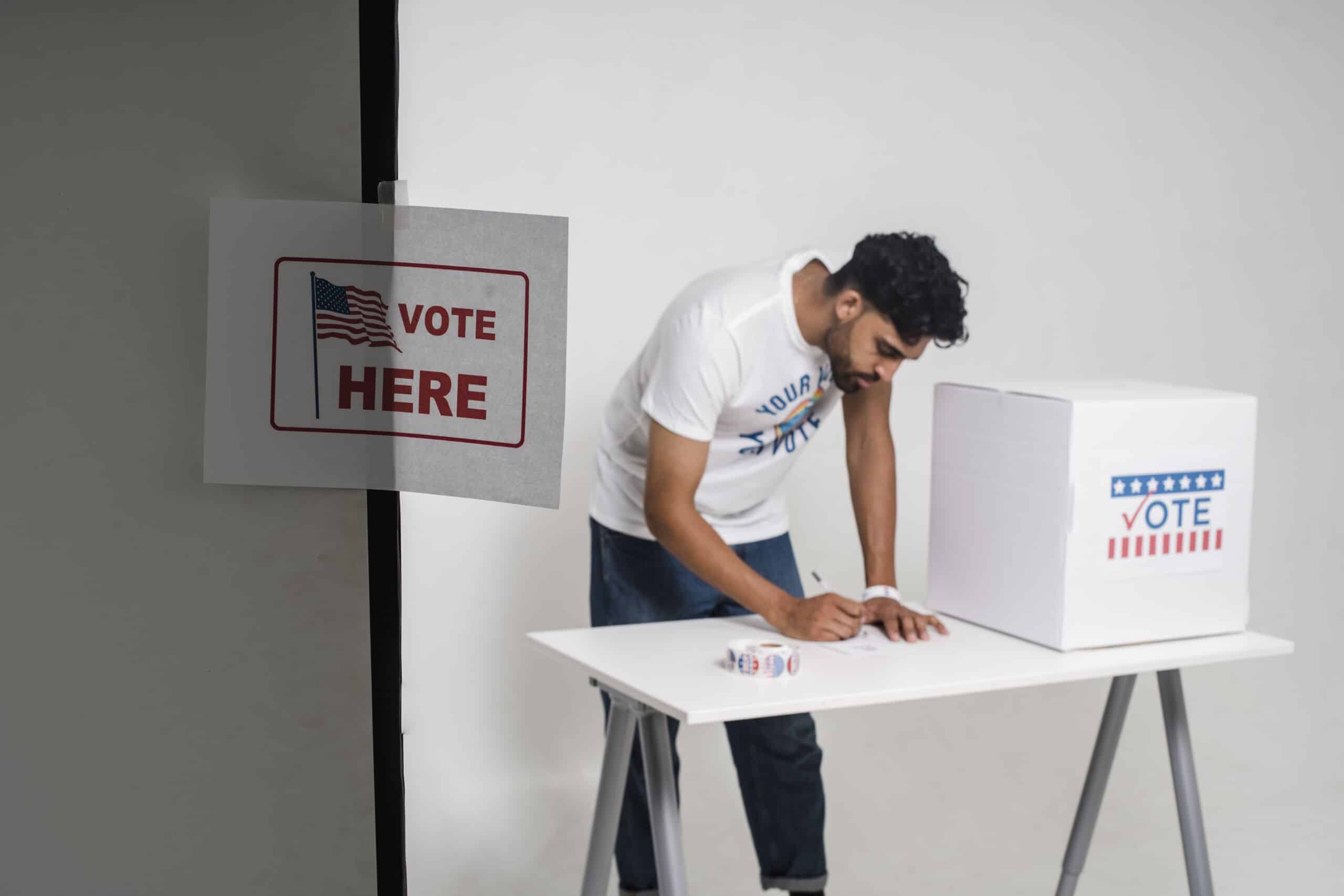 A man voting beside a ballot box